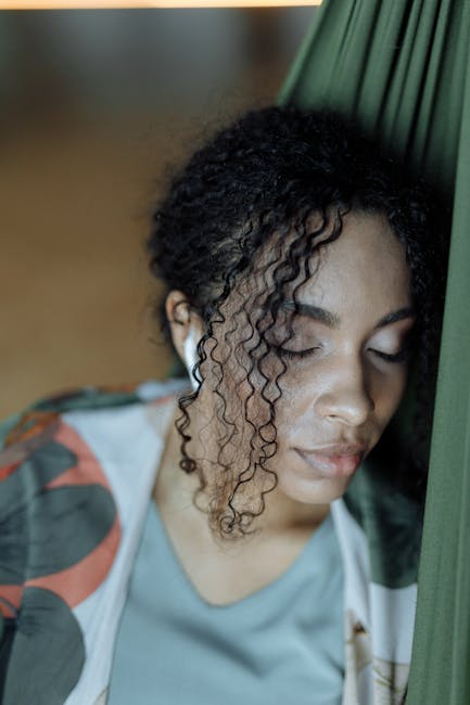 Woman practicing a serene yoga pose with closed eyes in a softly lit space
